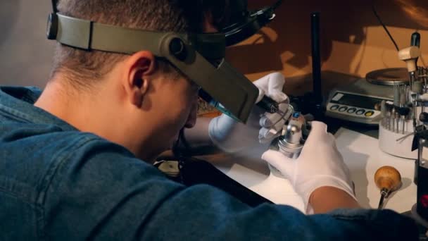 Bijoutier, orfèvre dans un atelier de bijoux professionnel travaille avec une bague avec pierre bleue dans un atelier de bijoux . — Video