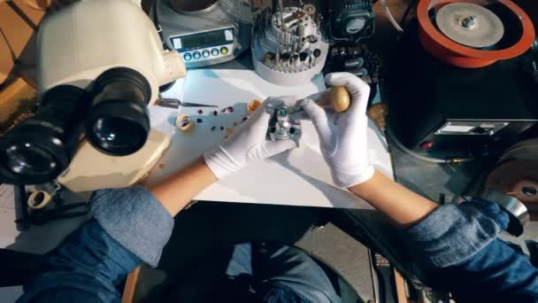 Joyero, orfebre en un taller de joyería profesional utiliza una llave, trabajando con un anillo de oro en un taller de joyería . — Vídeos de Stock