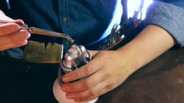 Çalışan kuyumcu bir yüzük üzerinde sarı mücevher taş yerleştirir.