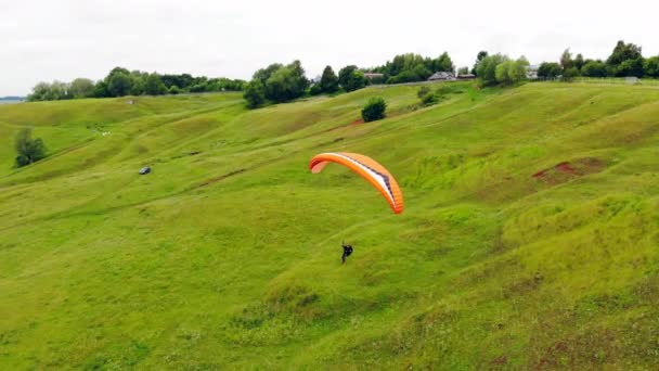 極端なスポーツコンセプト。人が緑の草原に沿ってパラフォイルを飛んでいる — ストック動画