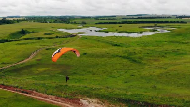 Een persoon gaat naar beneden terwijl hij de parawing vliegt. Paraglider vliegen. — Stockvideo