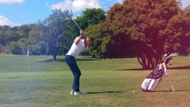 Молодой человек бьет по мячу клюшкой во время игры в гольф. Гольфер играет в гольф, спортивная концепция образа жизни . — стоковое видео