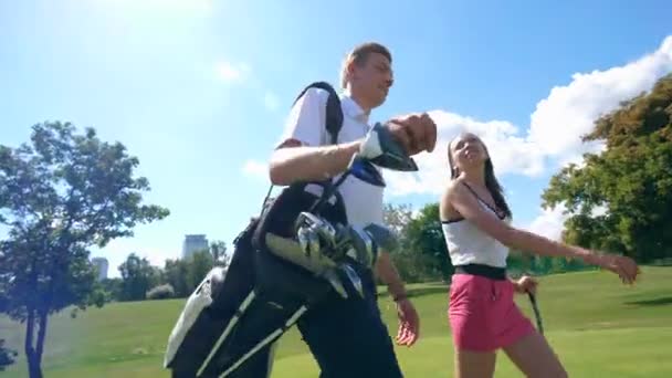 Жінка і чоловік ходять на поле для гольфу, розмовляючи . — стокове відео