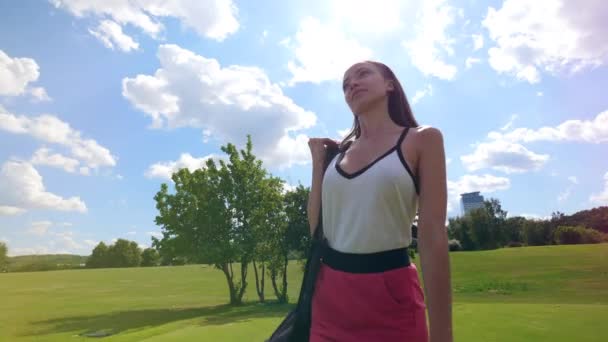 Giovane donna cammina su un campo da golf, tenendo una borsa con attrezzature . — Video Stock