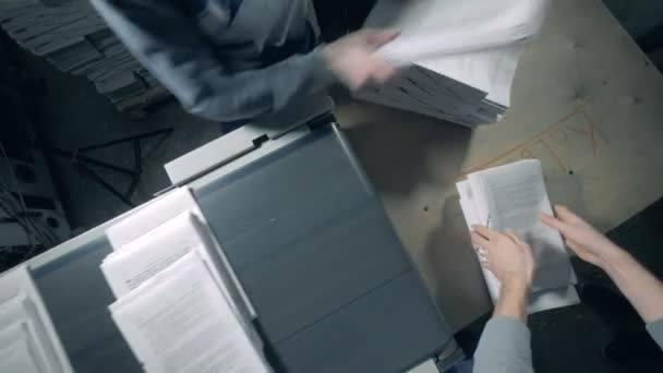 Los trabajadores recogen papel impreso de una línea tipográfica . — Vídeos de Stock