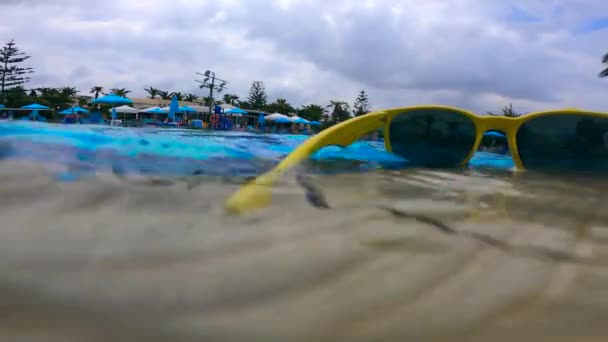 Solglasögon blir tvättas av poolen vatten — Stockvideo