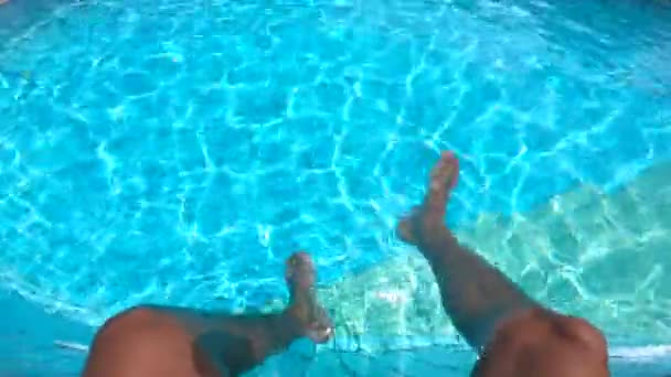 Schwimmbadwasser und Männerbeine, die darin schwingen — Stockvideo