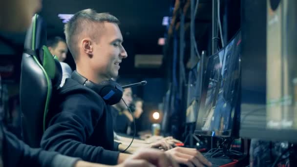 Vista lateral de um homem sorridente jogando jogo de computador em rede em um clube — Vídeo de Stock