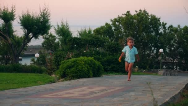 Mały chłopiec jest bieganie i chodzenie wzdłuż drogi morskiego kurortu — Wideo stockowe