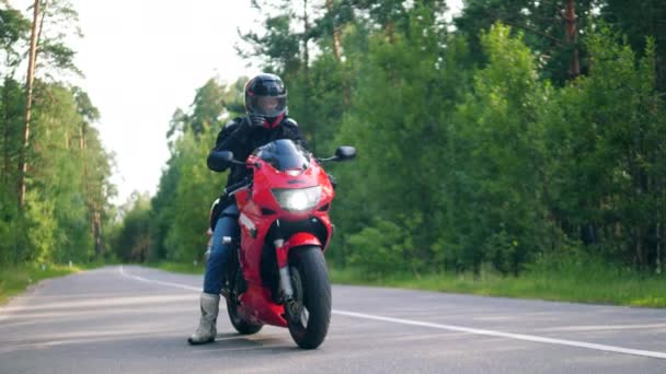 Eén persoon rijdt een rode motorfiets op een weg. — Stockvideo