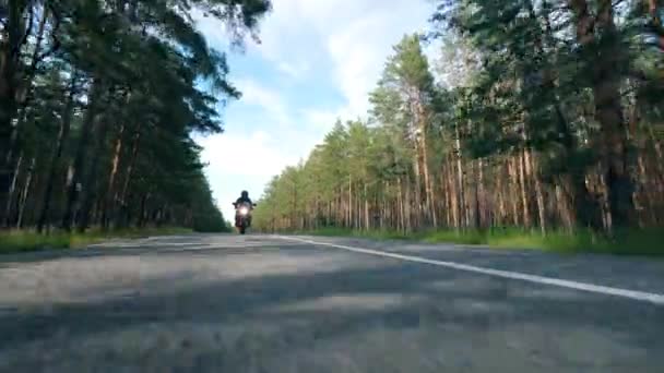 一人のモーターサイクリストが道路で赤い自転車に乗る. — ストック動画