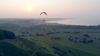 Yeşil sisli sahne boyunca sürüklenen bir parafoil ile. Paraşüt, yamaç paraşütü komseptisi.