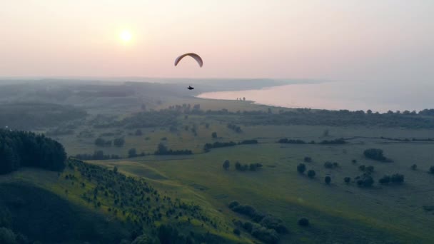 Grön dimmigt landskap med en parafoil drivande längs den. Fallskärm, skärmflygning comcept. — Stockvideo