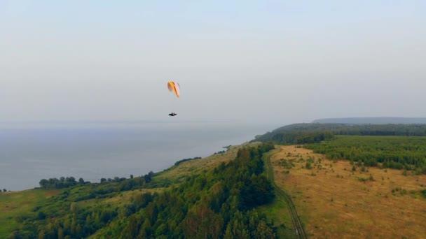 空中飞行器漂浮在水面和田野之上。跳伞者在天空中飞翔. — 图库视频影像