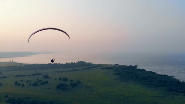 Paisaje acuático brumoso y una persona flotando en el parapente. Skydiver vuela en el cielo . — Vídeo de stock