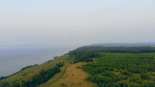 Erdei tengerpart és egy Kos-levegő ejtőernyő repülés mentén ez. Siklóernyős az égen. — Stock videók