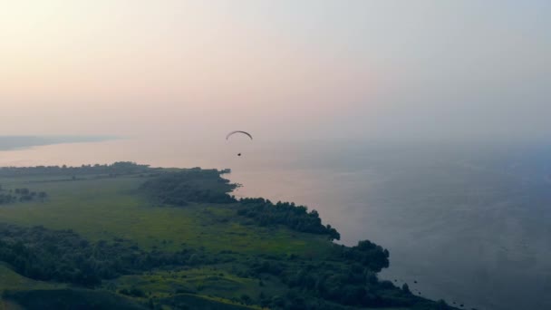 Paraglider seglar över dimmigt vatten landskap — Stockvideo