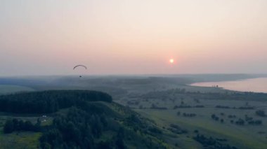 Paraplane gökyüzünde yüzerken güneş batıyor. Paraşüt, yamaç paraşütü komseptisi.