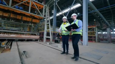 İki sanayi işçisi fabrikatesisinde yürüyor.