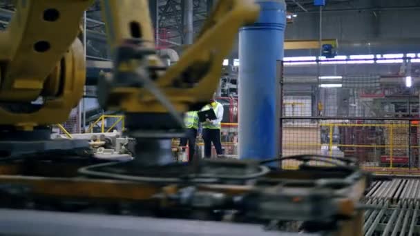 Instalación productora de ladrillos con dos trabajadores masculinos de pie en ella — Vídeos de Stock