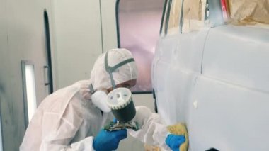 Asker bir bezle araba yüzeyini temizliyor