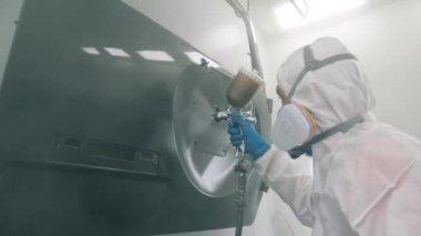 Erkek işçi bir otomobilin kapısını spreyle boyıyor