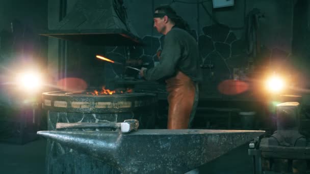 Un herrero clava un cuchillo caliente en el yunque . — Vídeo de stock
