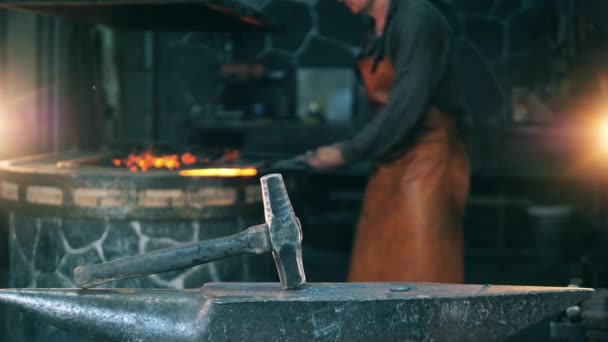 Un homme frappe un couteau avec un marteau, travaillant dans une forge. Forgeage de forge de métal fondu — Video