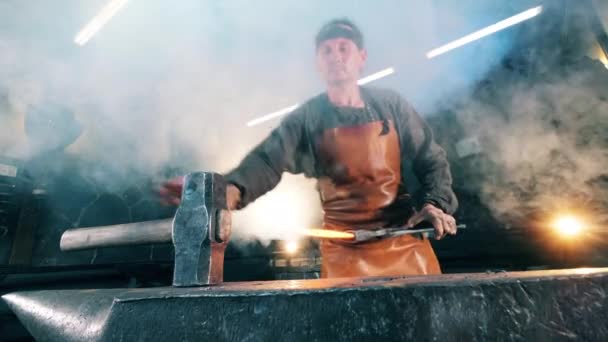 Le faussaire frappe un couteau chaud avec un marteau sur l'enclume. Forgeage de fer forgé en atelier . — Video