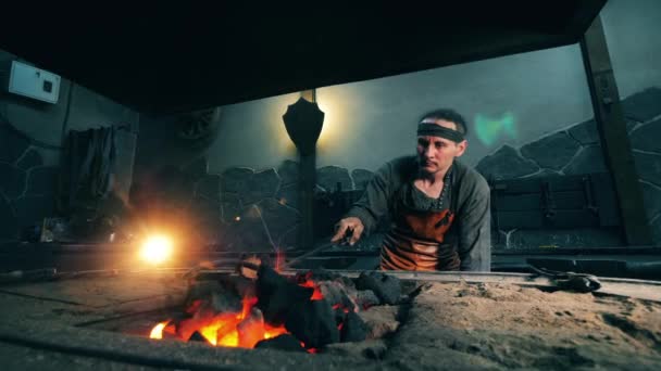 Один человек перевозит уголь в огне металлическим кочергой. Кузнец ковки железа в мастерской . — стоковое видео