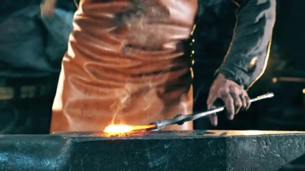 Un falsificador golpea cuchillo caliente con un martillo de metal. Herrero forjando hierro en taller . — Vídeos de Stock