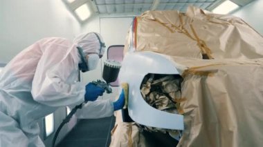 Erkek teknisyen renklendikten sonra otomobili siliyor.