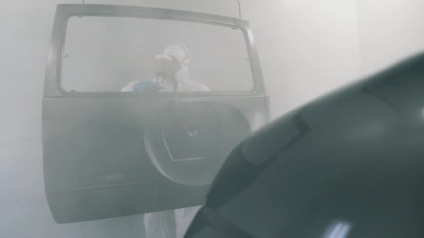 Механик раскрашивает дверь автомобиля с помощью опрыскивателя — стоковое видео