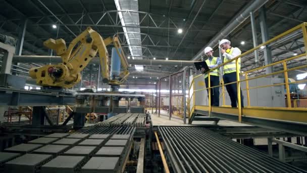 Werknemers bij een moderne installatie die nieuwe industriële robot apparatuur test. — Stockvideo