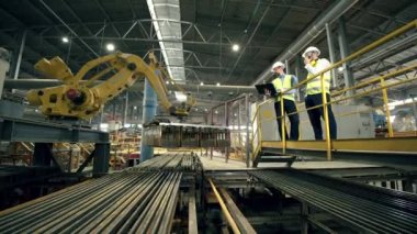 Erkek uzmanlar modern bir fabrikada tuğla yükleme sürecini kontrol ediyor.