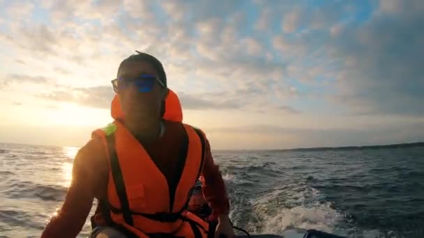 Un uomo con un giubbotto salvagente galleggia su una barca lungo il fiume — Video Stock