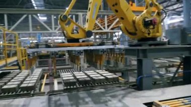 Robotik kol modern sanayi fabrikasında seramik ürünleri taşıyor.