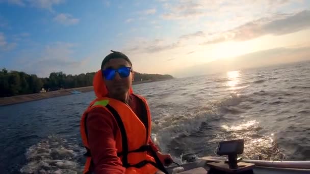 Riverbank en een man varen in een motorboot — Stockvideo