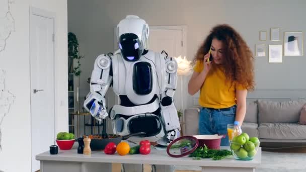 Ein Mädchen telefoniert, während ein Cyborg Essen kocht. futuristisches Konzept. — Stockvideo