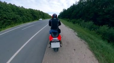 Motosikletçi otoban boyunca sürmeye başlar. Yolda motosiklet.
