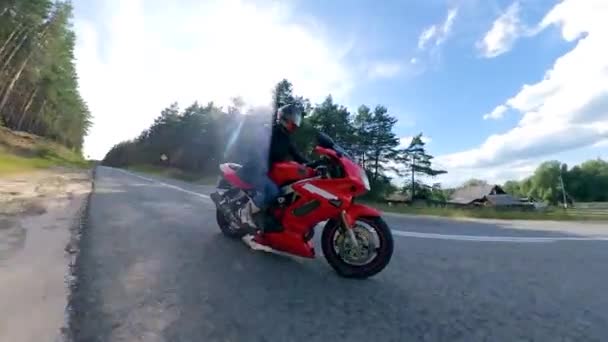 Motorfiets op een weg. Rode motorfiets in beweging met de chauffeur erop — Stockvideo