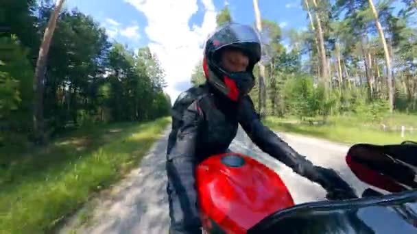 Вид сбоку на человека, который едет на мотоцикле по деревьям — стоковое видео
