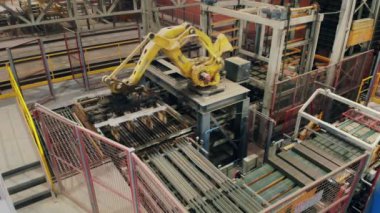 Bir fabrikada çalışan robotik kollar, hareketli tuğlalar.
