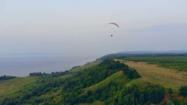 Yeşil yamaçlar ve üzerlerinde uçan parawing