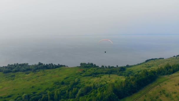 Eine Person im Gleitschirm fliegt über die Piste — Stockvideo