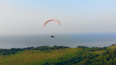 Yamaç paraşütü orman ve su üzerinde yüzüyor