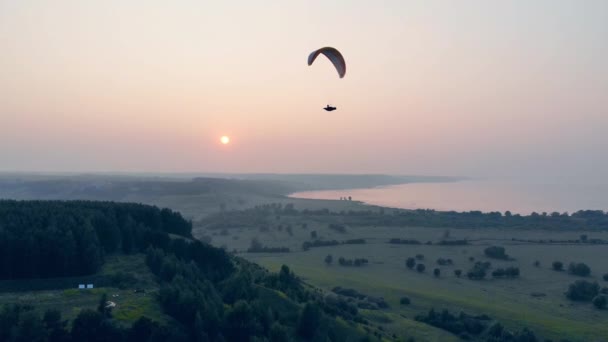 Een persoon in de paraplane vliegt hoog boven de grond — Stockvideo