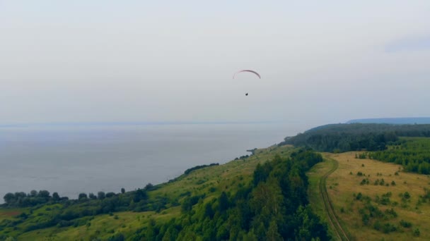 Paisagem aquática com colinas verdes e o parapente voando sobre eles — Vídeo de Stock
