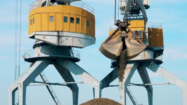 Crane with bucket unloads rubble at docks. — Stock Video