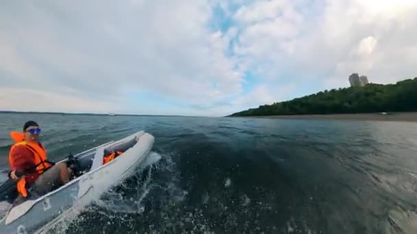 Un hombre se sienta en un barco mientras navega por el río . — Vídeos de Stock